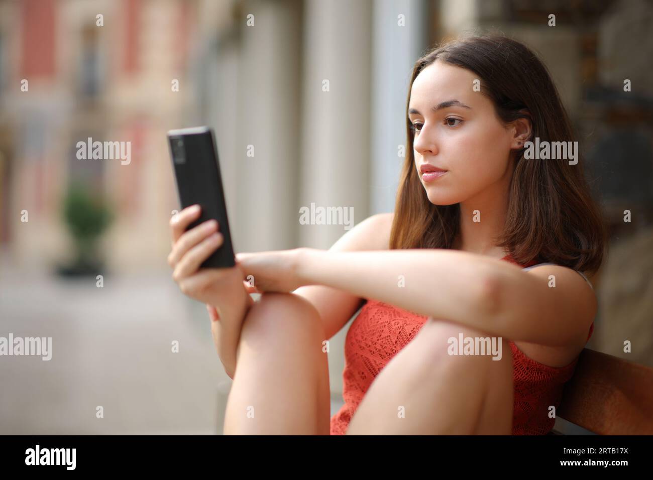 Eine ernsthafte Frau, die Telefoninhalte auf der Straße überprüft Stockfoto