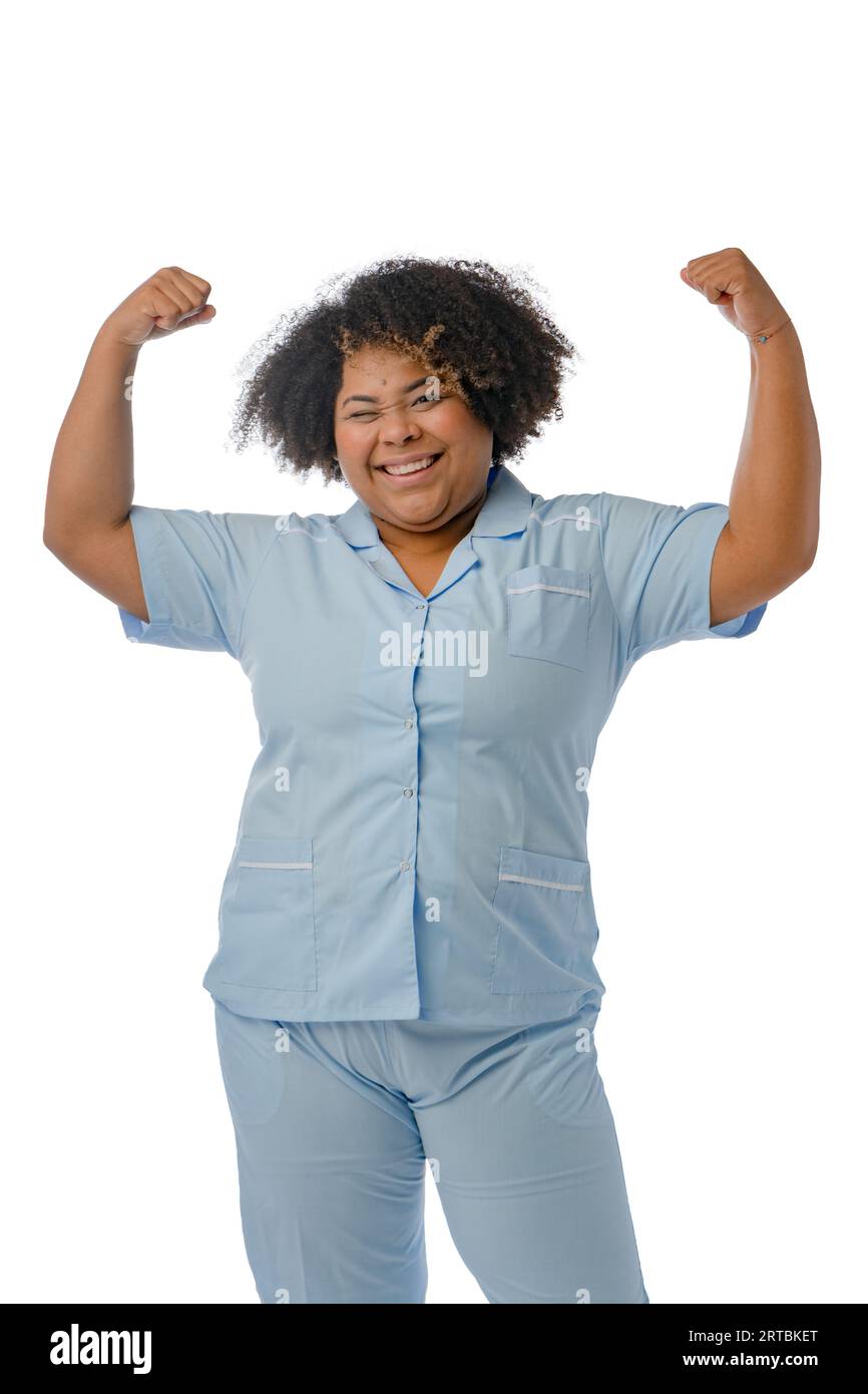 Porträt einer mächtigen venezolanischen Krankenschwester afro-lateinischer Herkunft in blauer Uniform, stehend lächelnd mit erhobenen Armen, die ihre Stärke und l zeigen Stockfoto