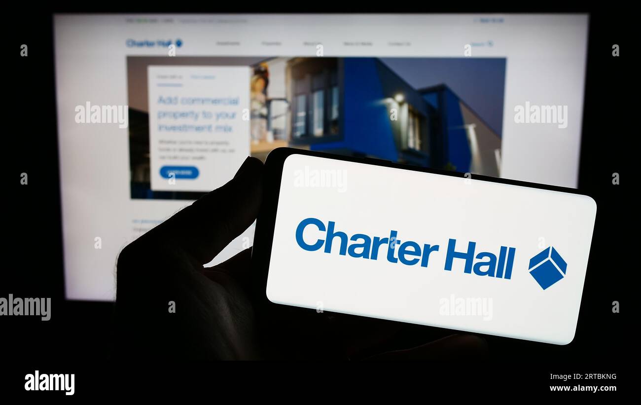 Person, die ein Smartphone mit dem Logo des Immobilienunternehmens Charter Hall Group auf dem Bildschirm vor der Website hält. Konzentrieren Sie sich auf das Display des Telefons. Stockfoto