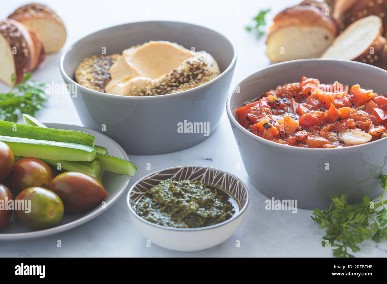 Vegetarische Vorspeisen: Hummus, gebratener Paprikasalat, Pesto und frisches Gemüse, Nahaufnahme. Veganes Lebensmittelkonzept. Stockfoto
