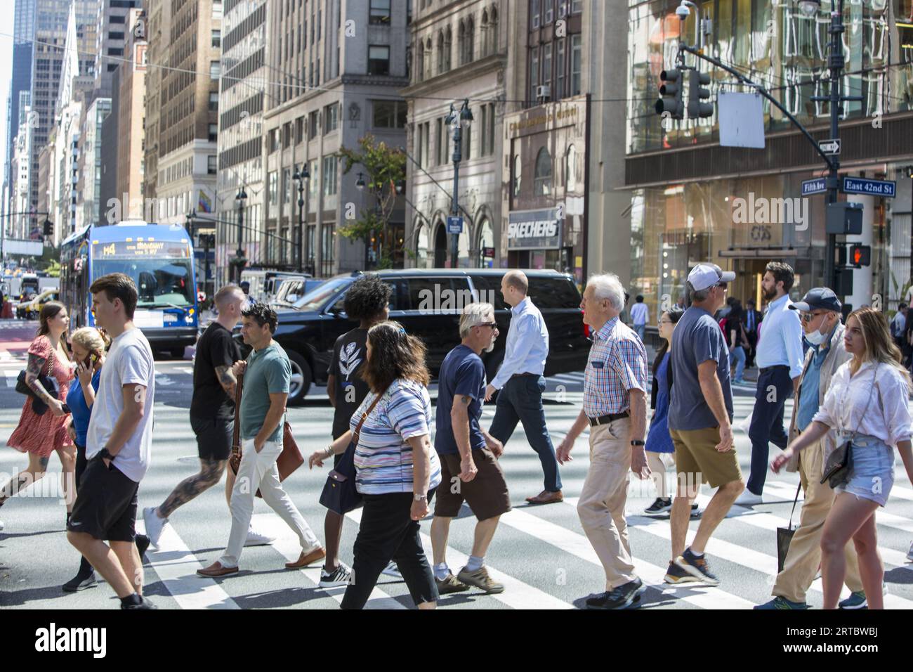 Menschen und Straßenverkehr an der immer überfüllten Ecke 42nd Street und 5th Avenue in Midtown Manhattan. Stockfoto