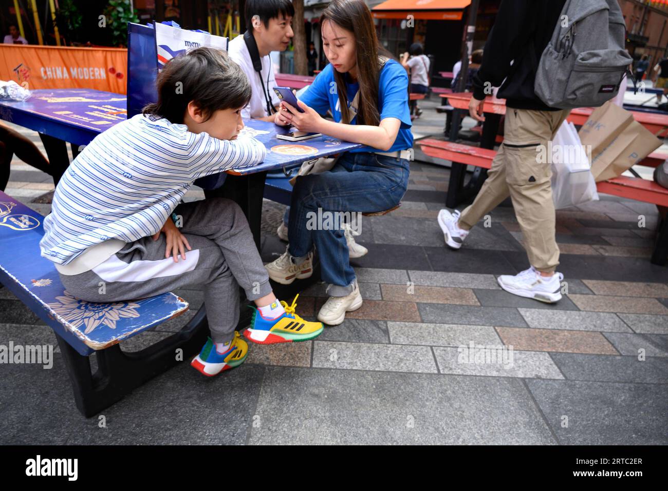 London, Großbritannien. Junge Familie, die draußen in Chinatown sitzt Stockfoto