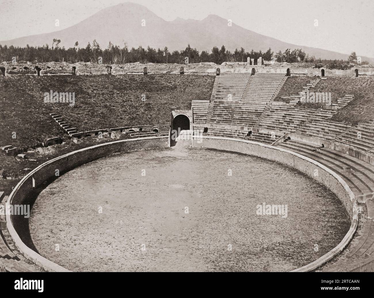 Archäologische Stätte Pompeji, Kampanien, Italien. Das ausgegrabene Amphitheater, wie es Ende des 19. Jahrhunderts war. Mt. Vesuv, der Vulkan, der die Stadt zerstörte, ist im Hintergrund zu sehen. Stockfoto