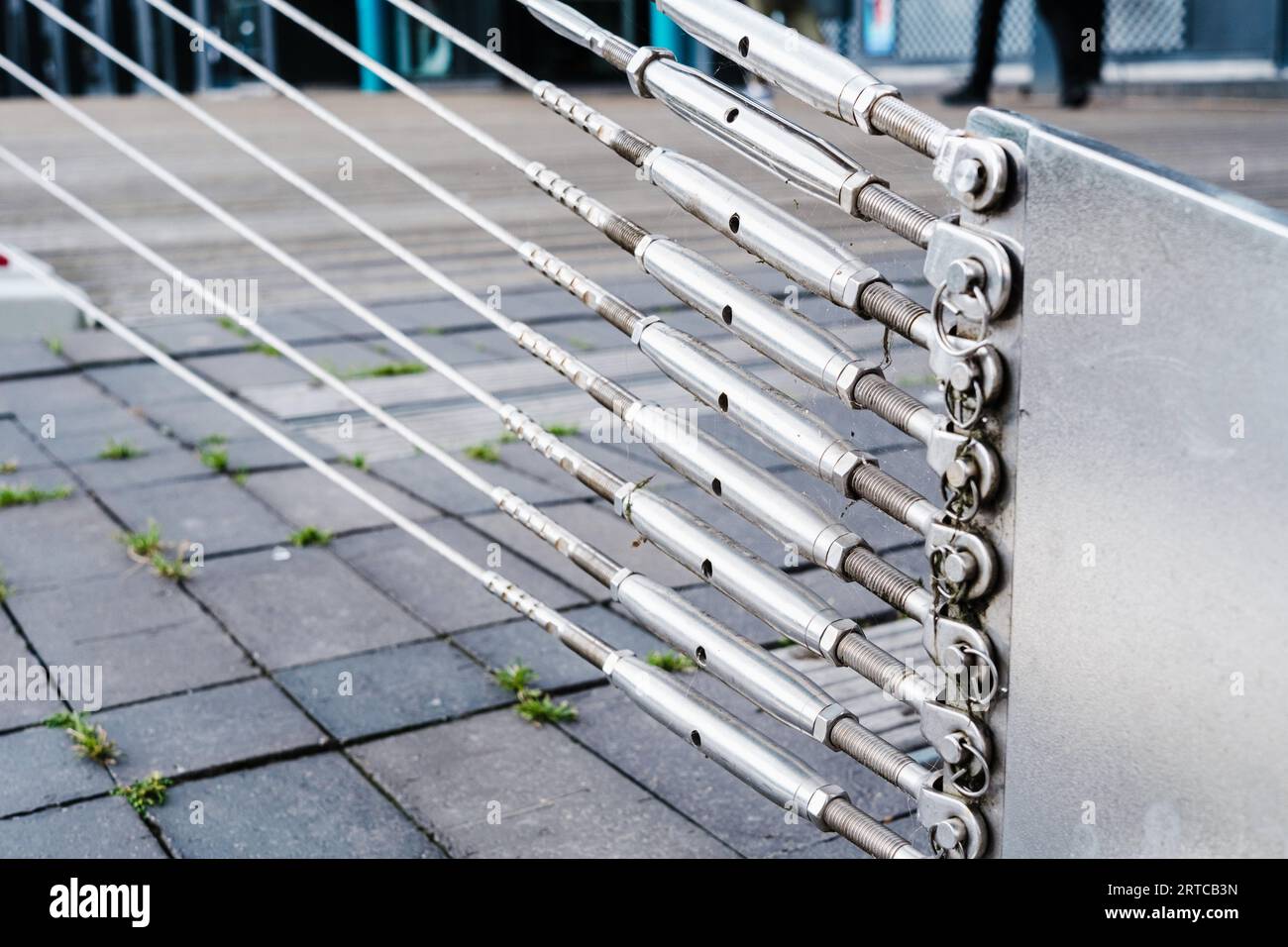 Stahlstreben, die an einer in den Boden geschobenen Stütze befestigt sind, halten die Stahlseile einer Brücke. Stockfoto