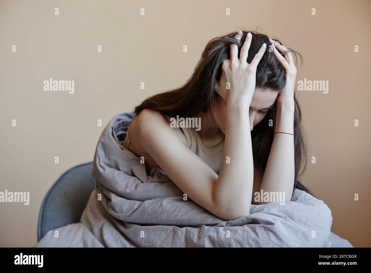 Porträt einer depressiven jungen Frau, die in eine Decke gehüllt ist, die mit psychischen Problemen zu kämpfen hat, Kopierraum Stockfoto