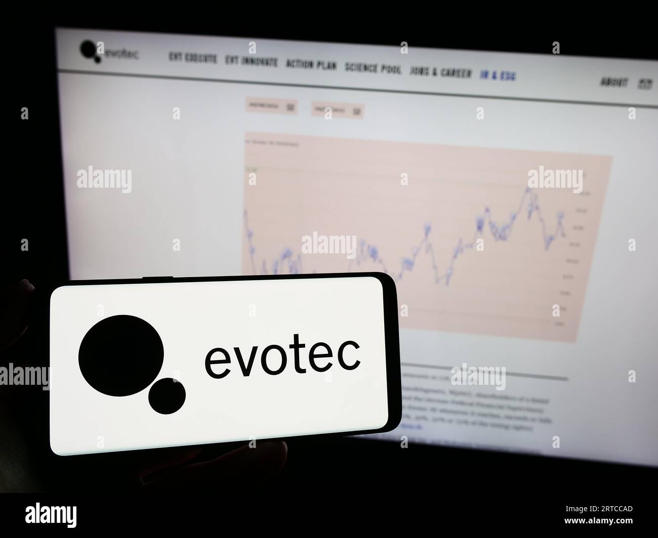 Person, die ein Mobiltelefon mit dem Logo des deutschen Arzneimittelforschungsunternehmens Evotec SE auf dem Bildschirm vor der Webseite des Unternehmens hält. Konzentrieren Sie sich auf das Display des Telefons. Stockfoto