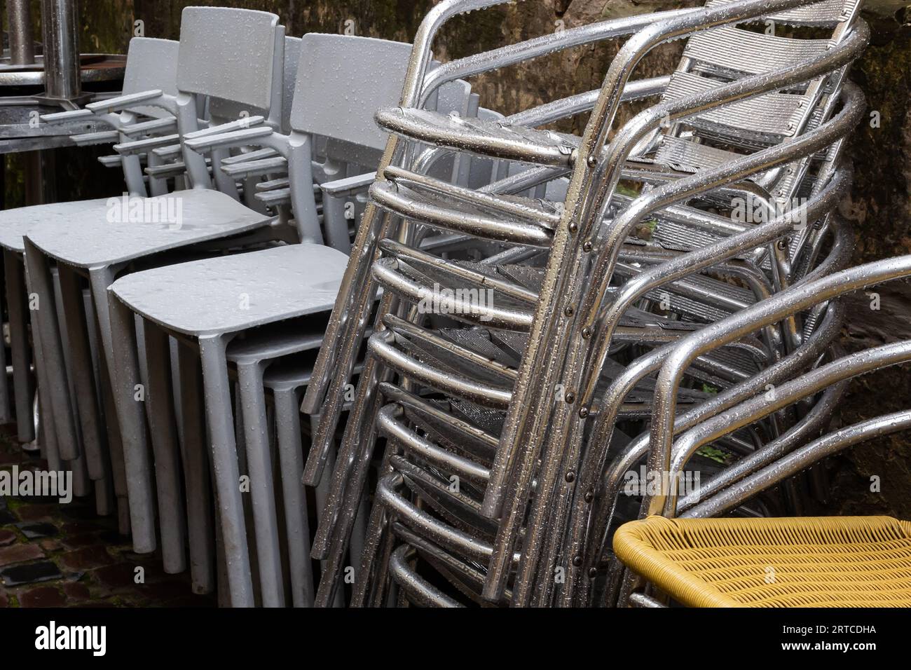 Die Stühle sind gefaltet. Polierte Tische aus Edelstahl vor einem Café, nass von Regen und Tau. Die Saison der Außenterrassen endet. Stockfoto