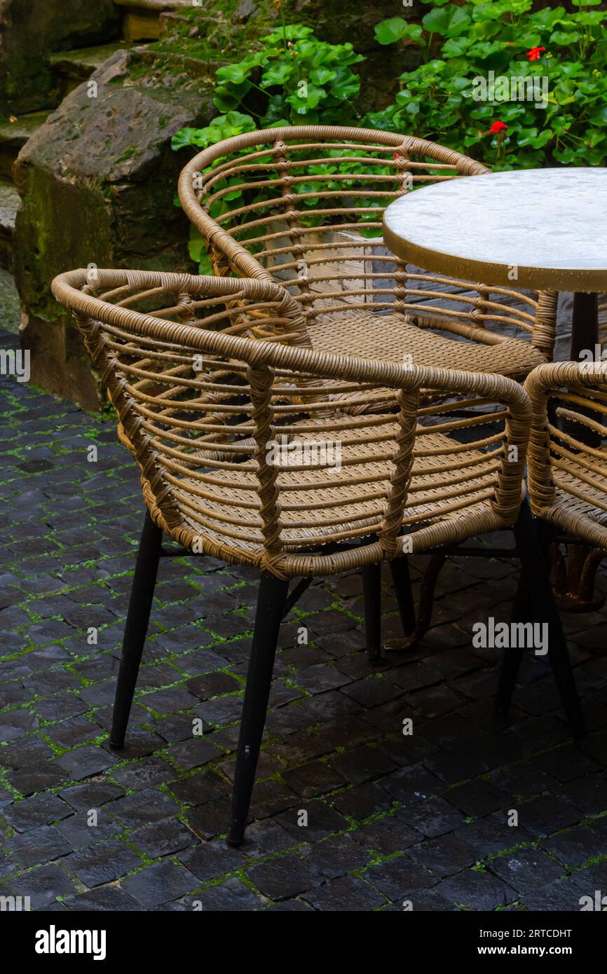 Leere nasse Holztische und -Stühle auf der Terrasse der Cafeteria im Freien bei Regen. Straßenleben im Regen. Stockfoto