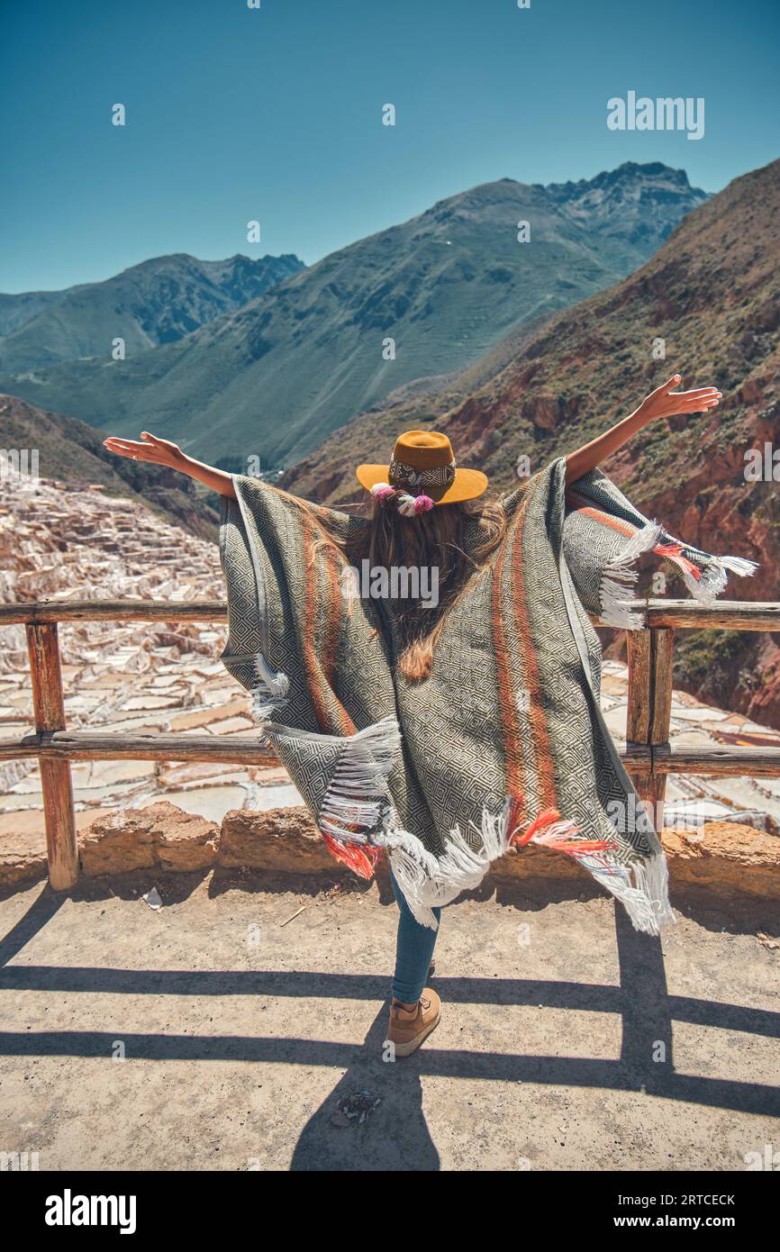 Weibliche Touristen mit in Hut und Poncho, die Maras Salzminen, Peru erkunden. Reise- und Fernweh-Konzept. Stockfoto