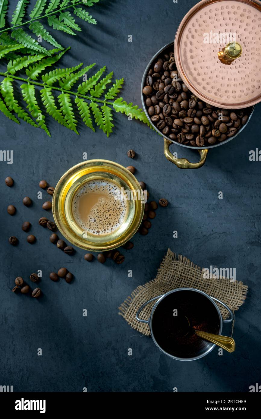 Südindischer Filterkaffee, serviert in einem traditionellen Messingbecher oder einer Tasse mit gerösteten rohen Kaffeebohnen. Traditioneller Filterkaffee, serviert in einer Messingtasse Stockfoto