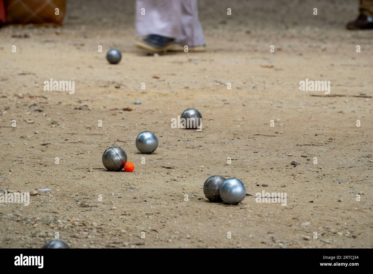 Petanque Ball Boules Schüsseln auf einem Staubboden, Foto beim Aufprall. Petanque-Spiel auf dem Boden. Kugeln und einen kleinen Holzheber. Stockfoto