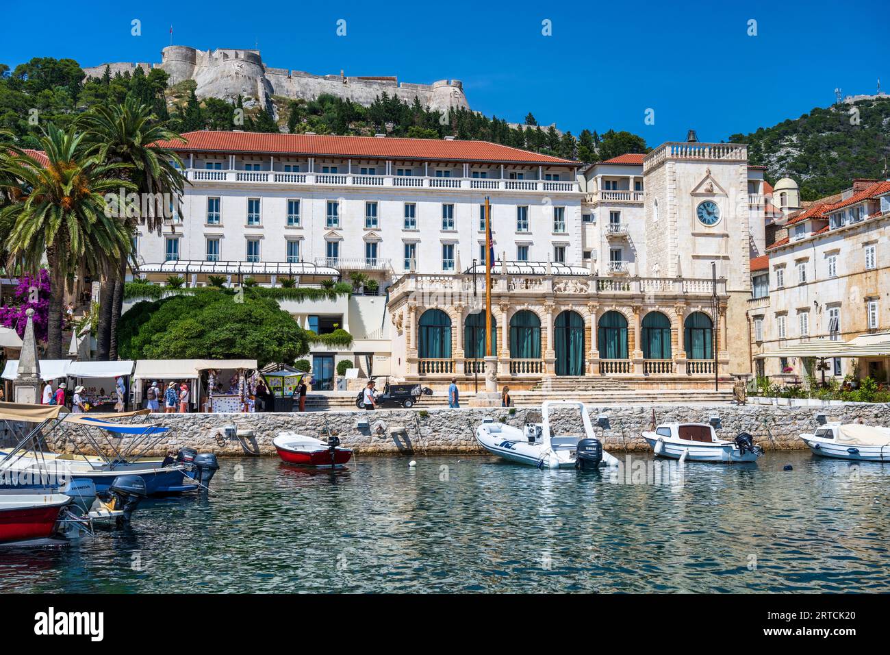 Palace Hotel, Loggia und Uhrenturm, mit spanischer Festung auf einem Hügel über Hvar Stadt (Grad Hvar) auf der Insel Hvar an der dalmatinischen Küste von Kroatien Stockfoto