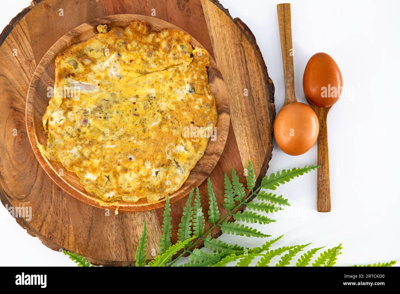 Würziges Pfefferomelett, hausgemacht und verzehrfertig in einem Holzteller. Braune Omelettes in Holzplatte und isoliert. Indisches hausgemachtes, würziges Omelett. Stockfoto