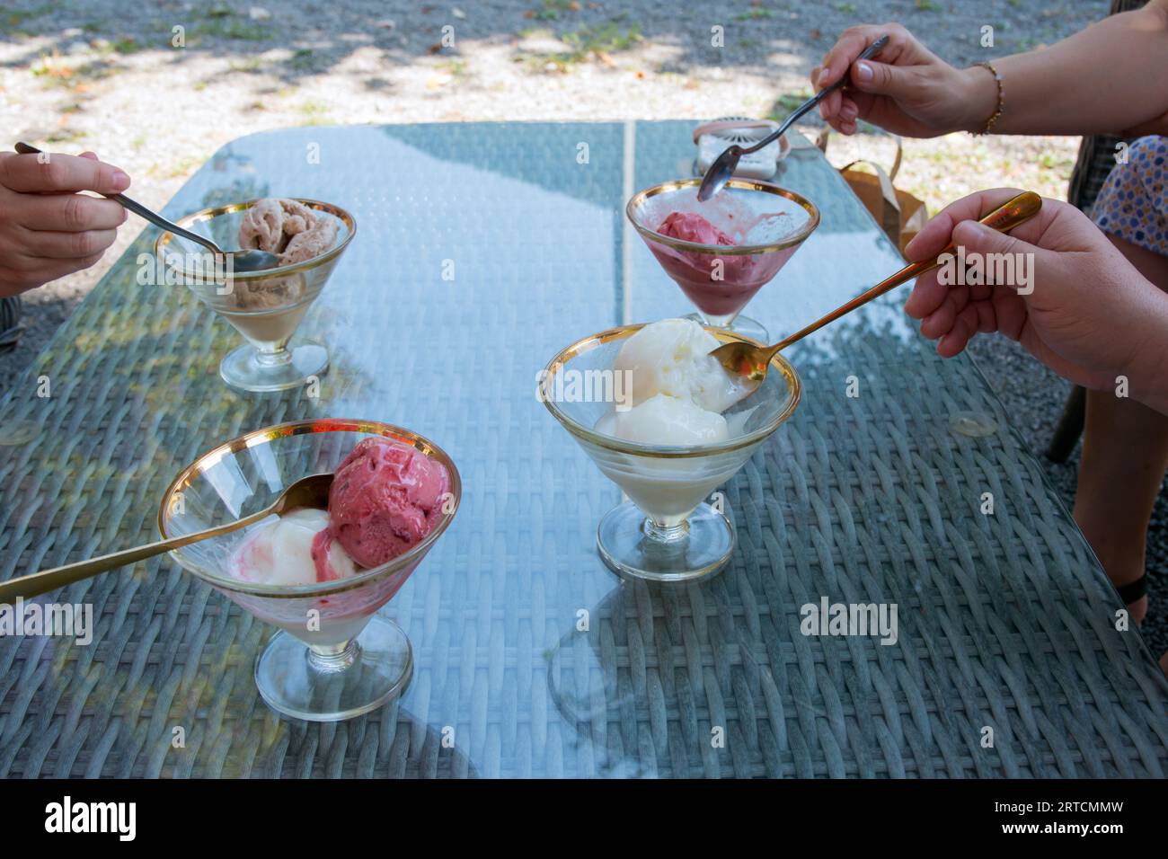 Freunde genießen Eisdesserts mit goldenen Löffeln Stockfoto