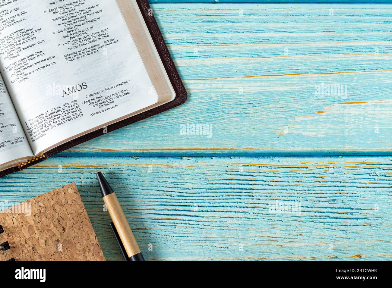 Amos öffnet das Heilige Bibelbuch auf einem rustikalen Holztischhintergrund mit Notizbuch und Stift. Leerzeichen kopieren. Alte Testament-Prophezeiung studieren, christliches Konzept. Stockfoto