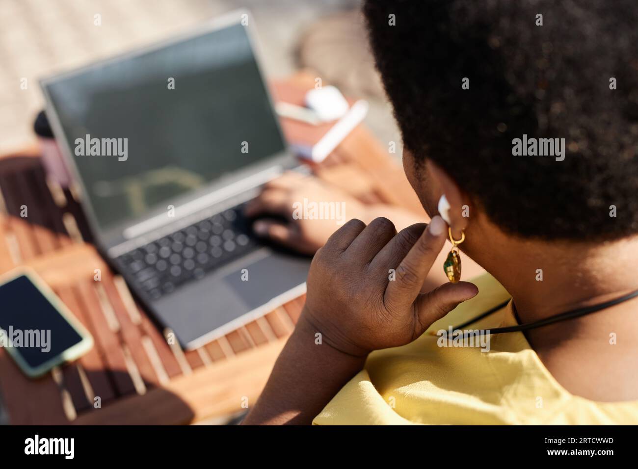 Nahaufnahme von Black Woman, die bei der Arbeit mit einem Laptop im Freien auf schnurlose Kopfhörer klopft, Kopierraum Stockfoto