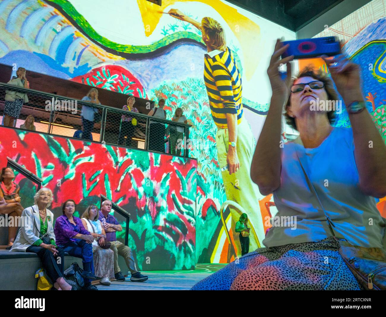 Besucher der Ausstellung „David Hockney: Bigger & Closer (Not smaller & further away)“ mit großformatiger Projektion im Lightroom in King's Cross, London, fotografieren und genießen das immersive Erlebnis am Dienstag, den 12. September 2023. David Hockney nimmt die Besucher mit auf eine persönliche Reise durch sechzig Jahre seiner Kunst Die riesigen Wände und das revolutionäre Soundsystem von Lightroom ermöglichen es Besuchern, die Welt durch Hockneys Augen zu erleben. Die Ausstellung läuft bis zum 3. Dezember 2023. Rob Taggart/Alamy Live Stockfoto