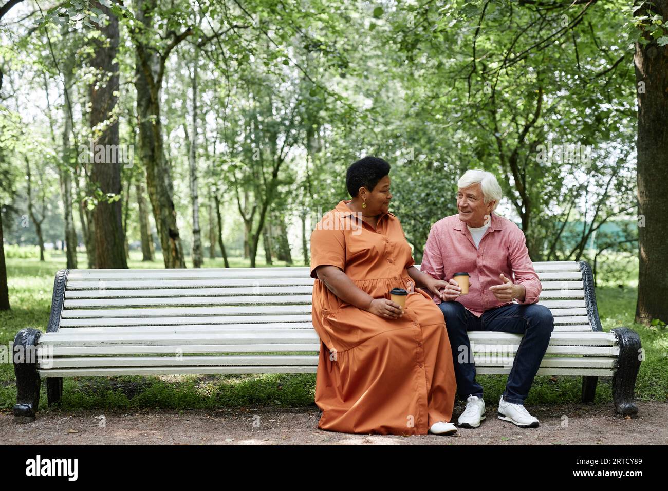 Porträt in voller Länge von glücklichem Seniorenpaar, das draußen auf einer Parkbank sitzt und kopierbar ist Stockfoto