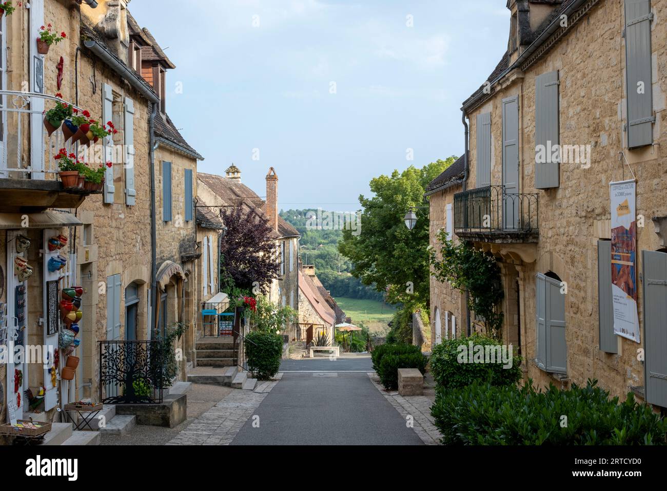 Domme, Frankreich – malerische Straße mit Steinhäusern und blühenden Blumen im historischen Dorf Domme im Dordogne-Tal. Stockfoto