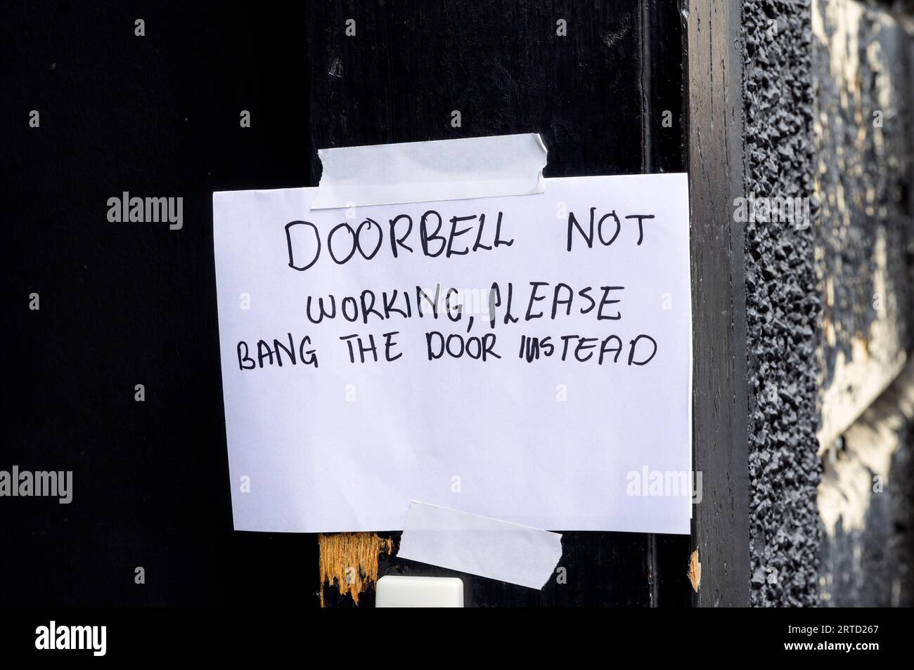 Eine handschriftliche Notiz, die Besucher anweist, eine Tür zu knallen, weil die Türklingel gebrochen ist Stockfoto