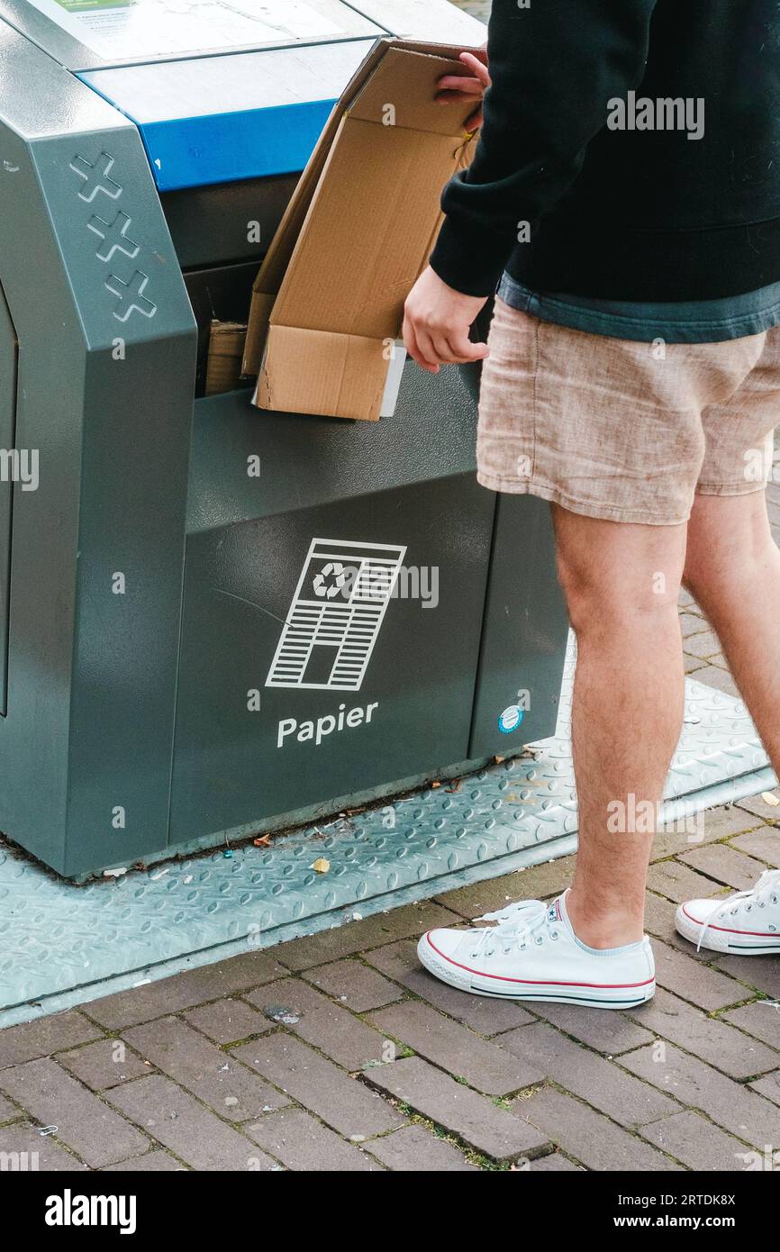 Bilder einer Person, die vor einem unterirdischen Papierkorb mit blauem Deckel steht, und die drei X symbolisieren die Stadt Amsterdam. Stockfoto