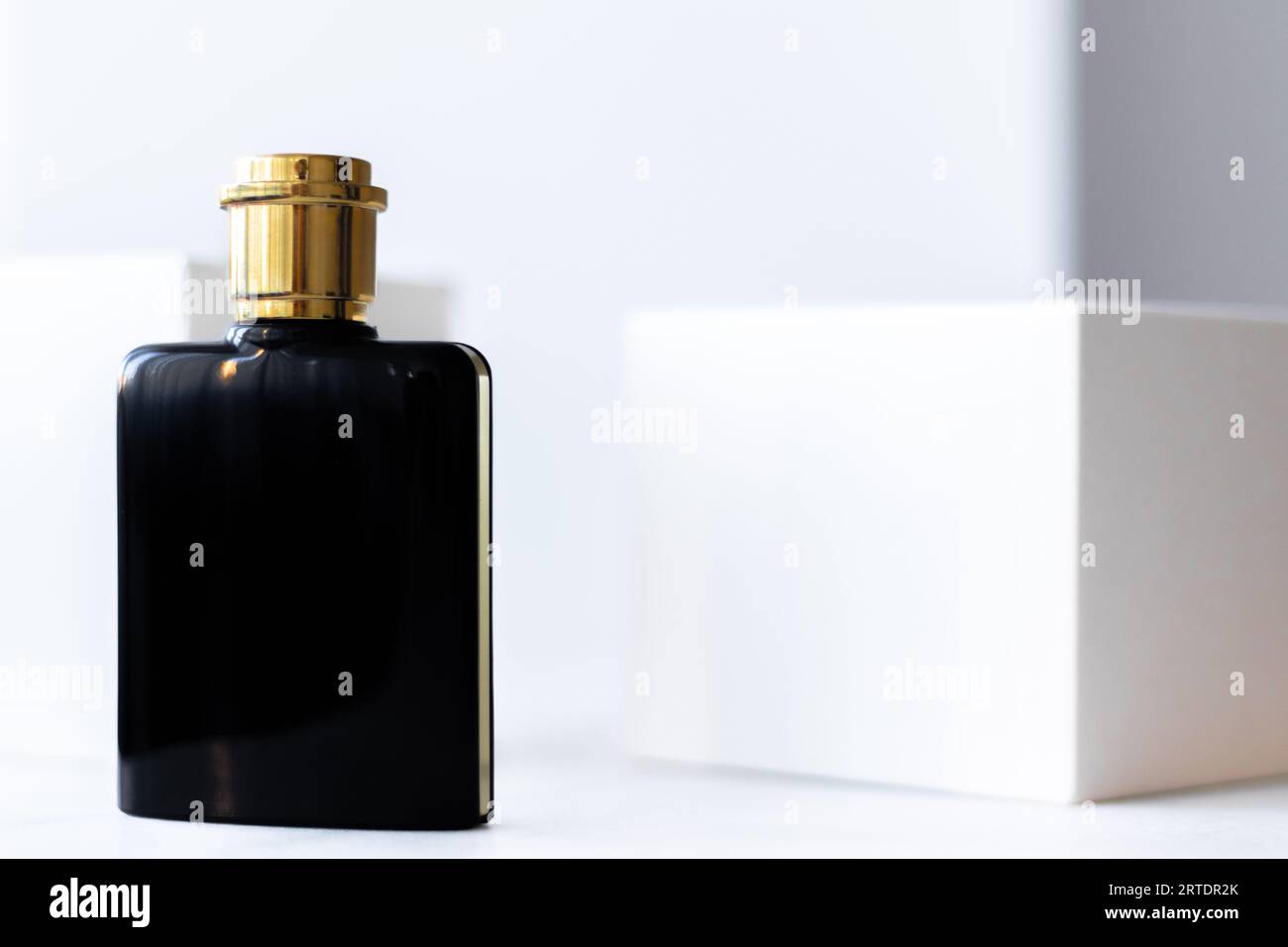 Schwarze Parfümflasche mit goldenem Verschluss auf weißem Hintergrund Stockfoto