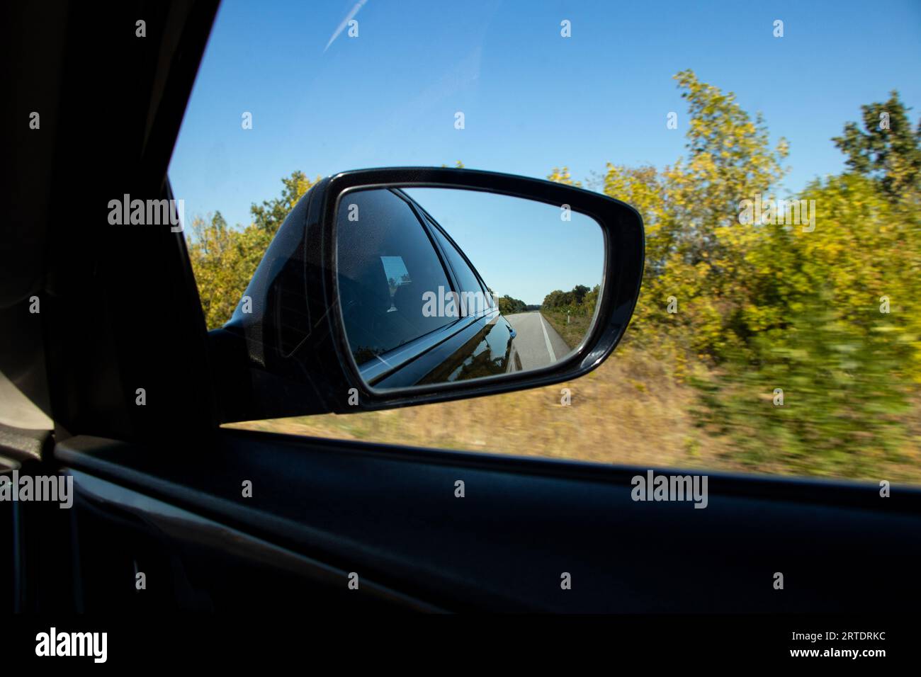 Blick in den Rückspiegel in einem fahrenden Auto entlang der Autobahn in der Ukraine im Sommer im Urlaub tagsüber, Straße, Blick in den Autospiegel Stockfoto