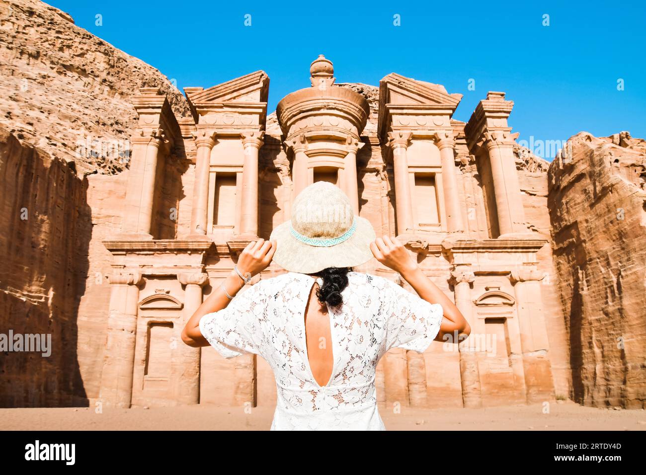 Filmische Petra Hintergrund kaukasische junge Frau in weißem Kleid und Hut genießen Petra A'deir Kloster, Petra's größtes Denkmal, UNESCO World Herita Stockfoto