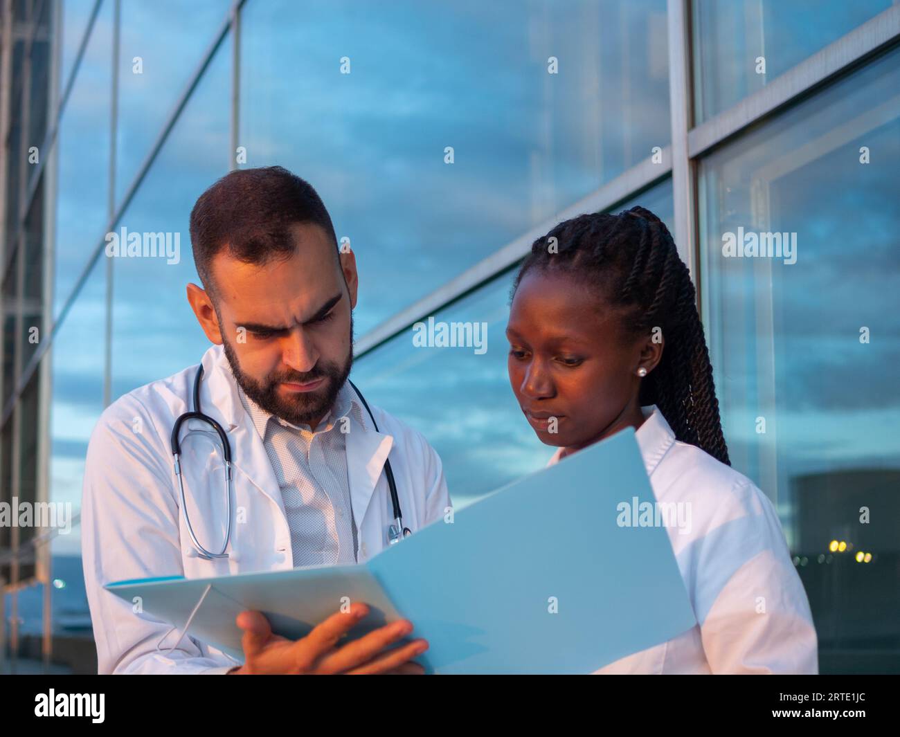 Zwei Krankenhausärzte, eine Frau und ein Mann, machen eine Pause im Freien. Einige Dokumente werden geprüft. Stockfoto