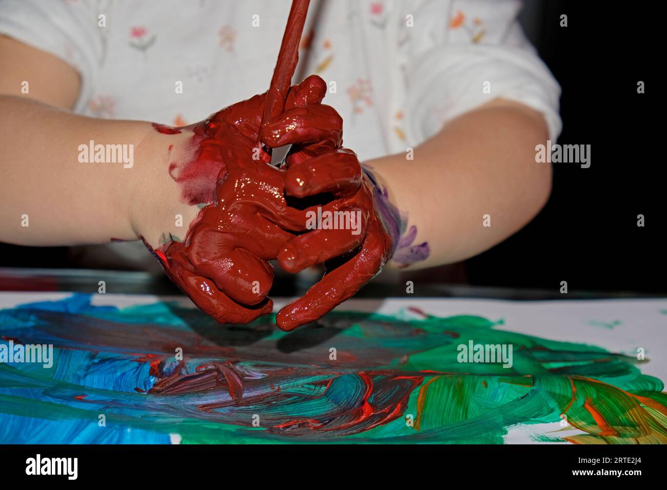 Kinderhände versuchen, mit Pinsel und Farbe zu zeichnen Stockfoto