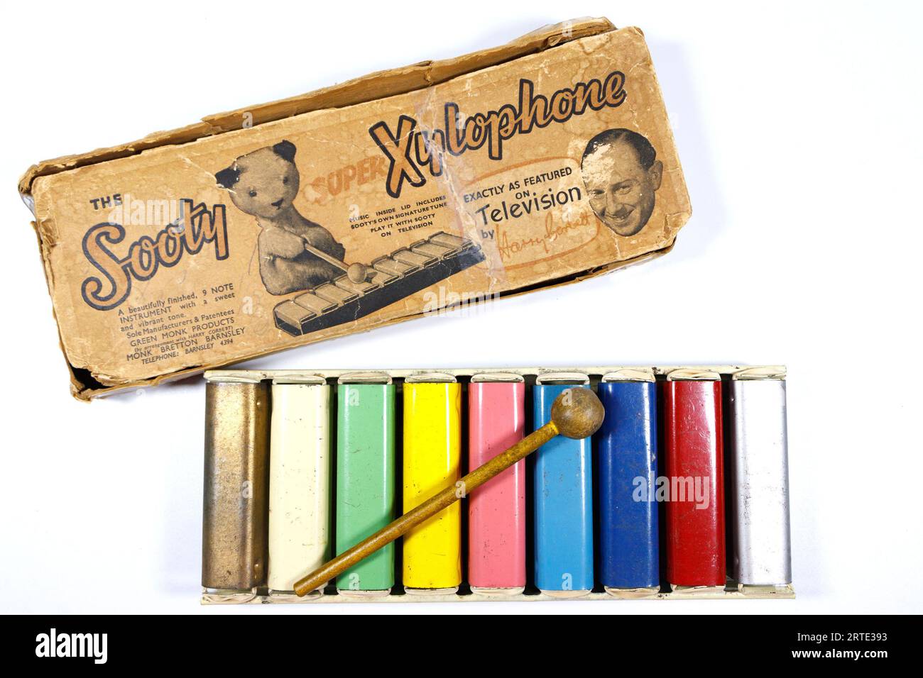 Vintage-Ruß-Xylophon-Spielzeug mit bunten Metallstäben und Hammer, zusammen mit dem original abgenutzten Karton mit Illustrationen. Stockfoto