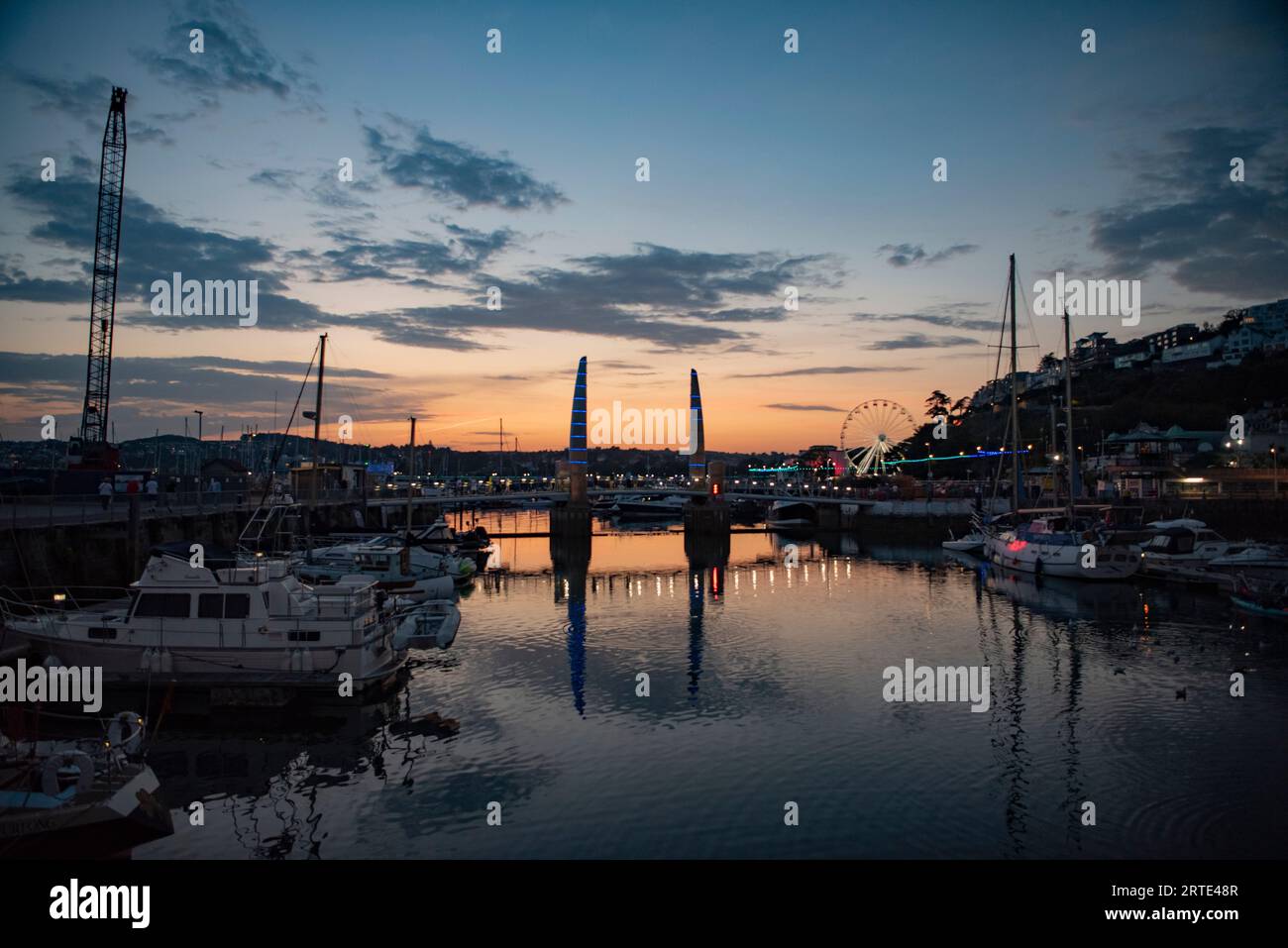 Sonnenuntergang im September im Torquay Harbour, Torbay. Blick auf viele Boote im Yachthafen, die cill-Tore/Brücke, mit dem großen Rad in der Ferne. Englisch Stockfoto