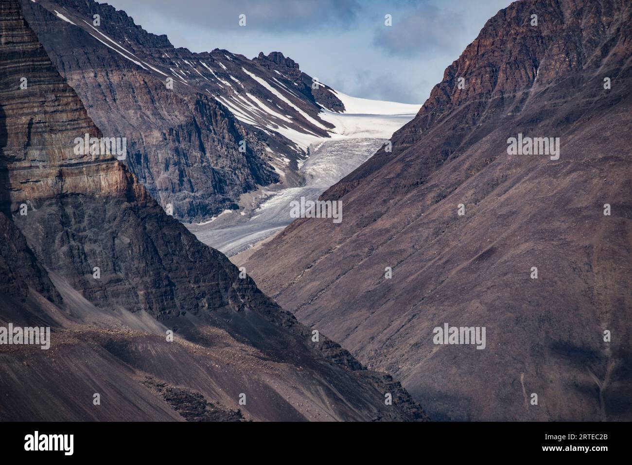 Blick durch die bergige Landschaft zu einer eisigen Gletschermasse im Kong Oscar Fjord von Grönland; Ostgrönland, Grönland Stockfoto