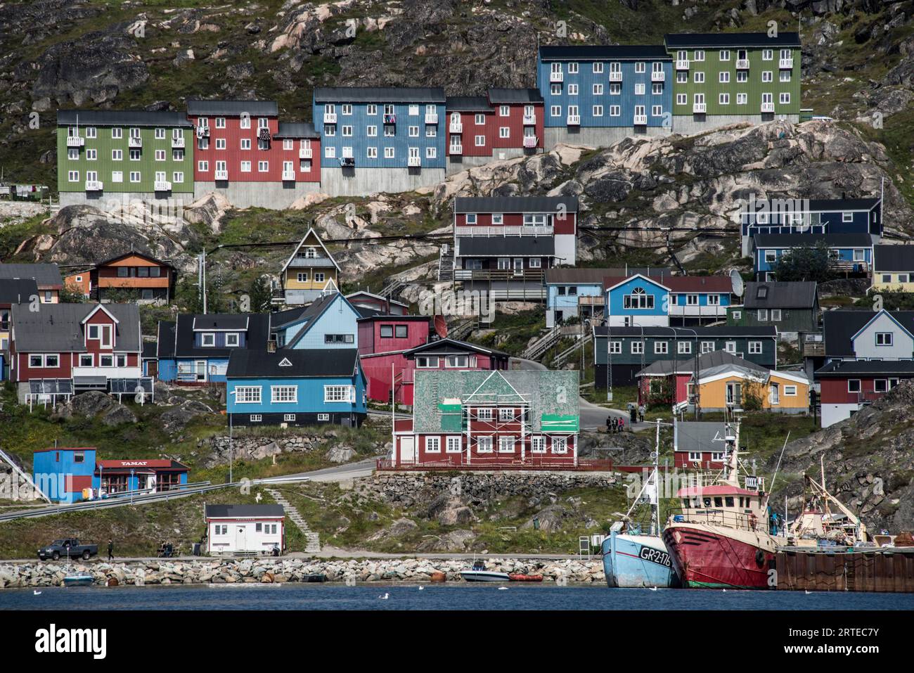 Nahaufnahme der farbenfrohen Gebäude auf den felsigen Klippen entlang der Küste in der Seehafenstadt Qaqortoq an Grönlands Südspitze Stockfoto