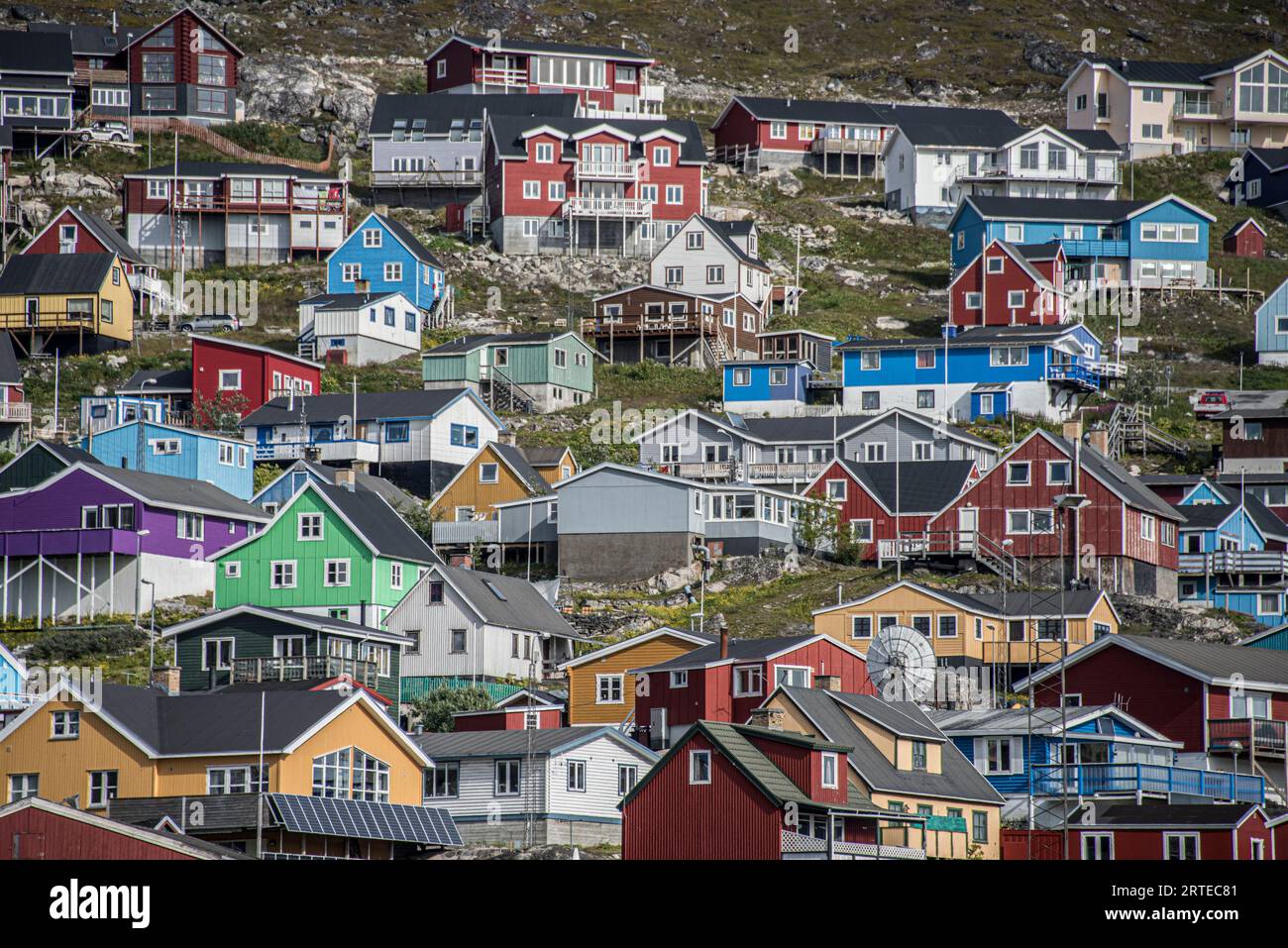 Nahaufnahme der farbenfrohen Gebäude auf den felsigen Klippen entlang der Küste in der Seehafenstadt Qaqortoq an Grönlands Südspitze Stockfoto
