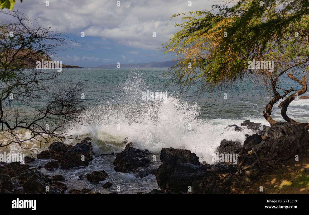 Wellen schlagen unter bewölktem Himmel an der felsigen Küste in Makena Landing, Kihei, Maui, Hawaii, Vereinigte Staaten von Amerika Stockfoto