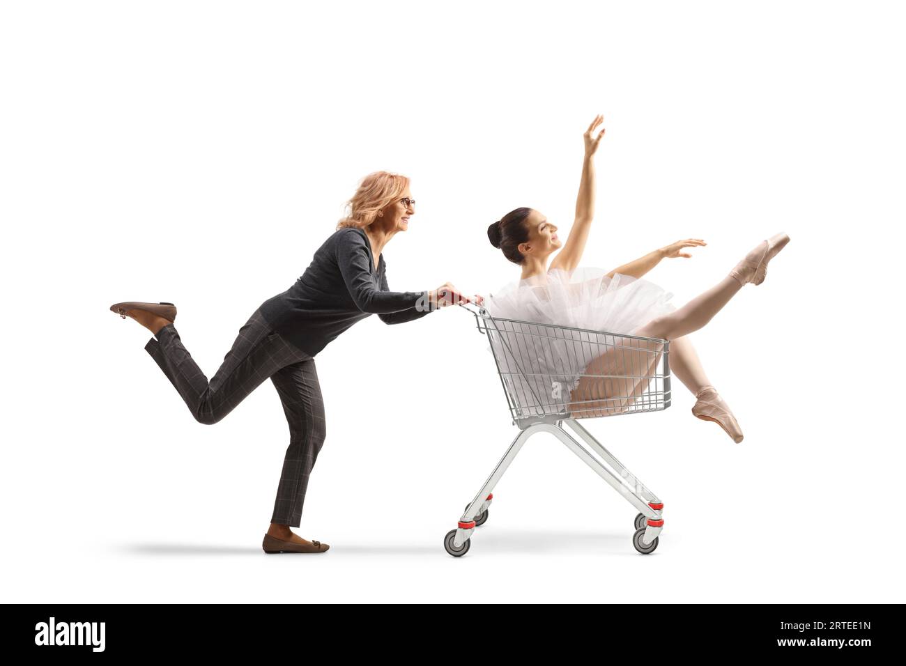 Reife Frau, die in einem Warenkorb auf weißem Hintergrund läuft und eine Ballerina schiebt Stockfoto
