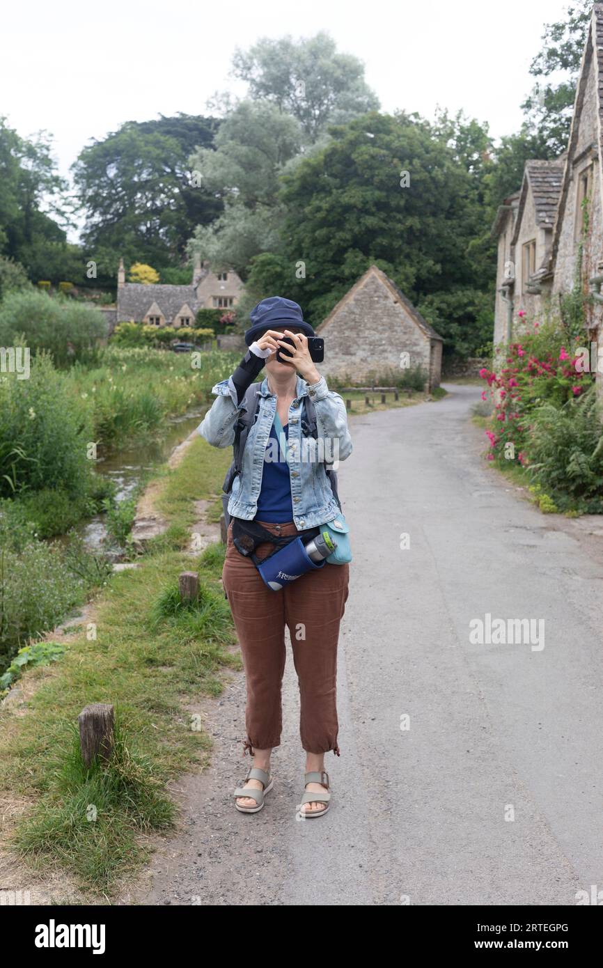 Reife Frau nutzt ihr Smartphone auf Reisen im Freien; Großbritannien Stockfoto