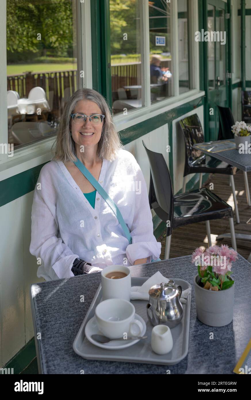 Reife Frau sitzt mit Kaffee in einem Café; Großbritannien Stockfoto