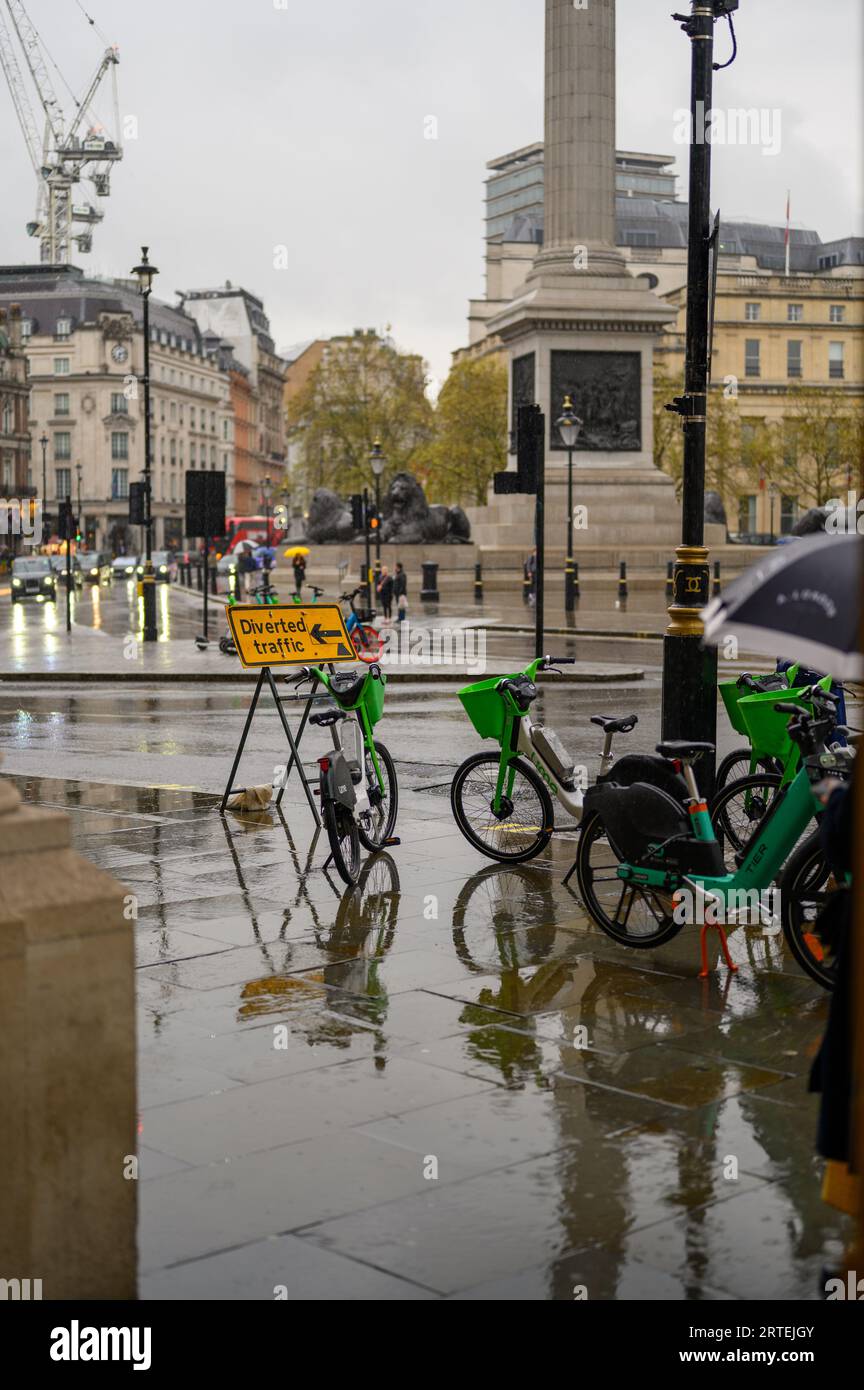 LONDON - 24. April 2023: Erkunden Sie London an einem regnerischen Tag mit Leihfahrrädern am Trafalgar Square. Stockfoto