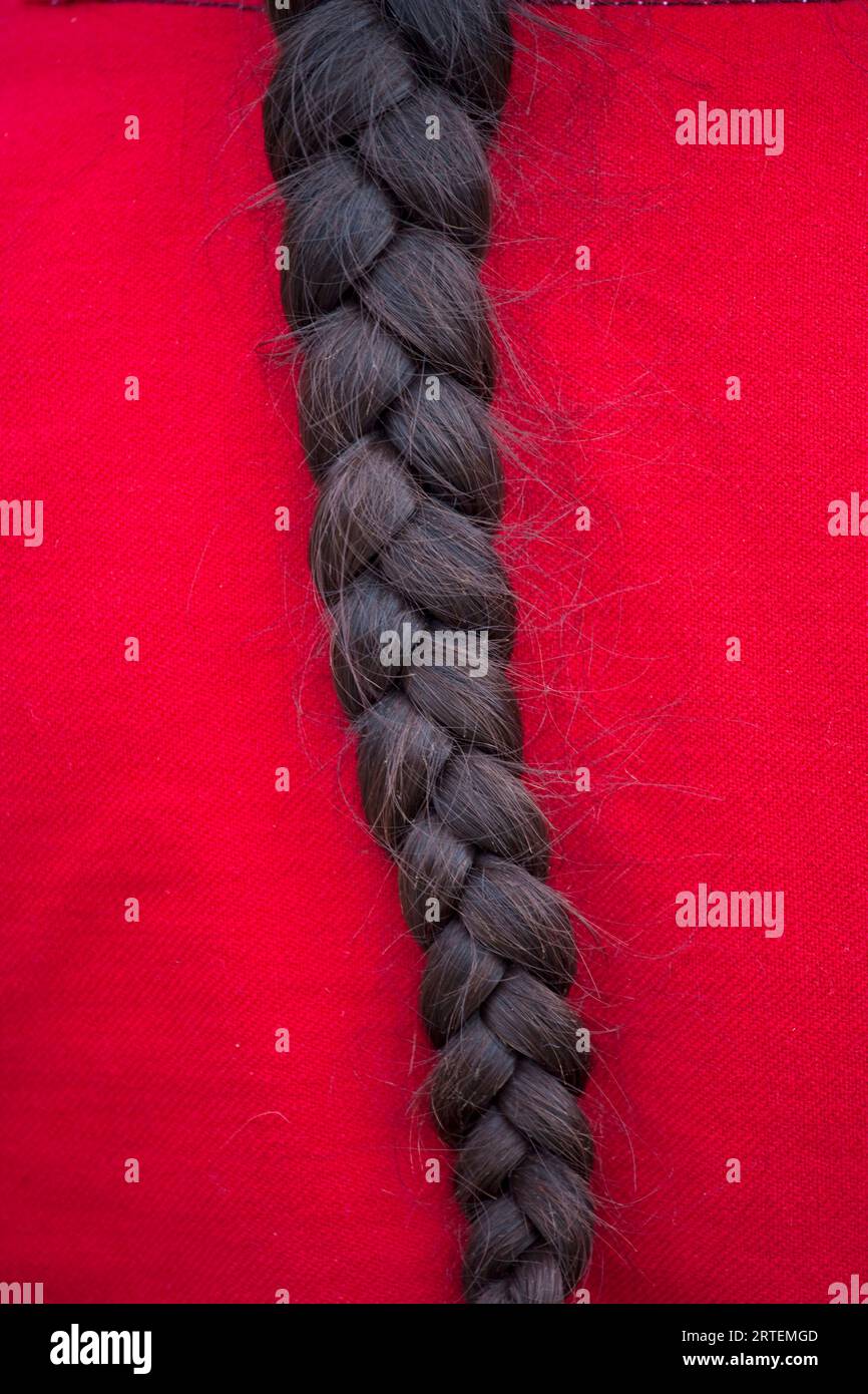 Nahaufnahme des dunklen Haarklochs einer Frau auf rotem Material; Sacred Valley, Peru Stockfoto