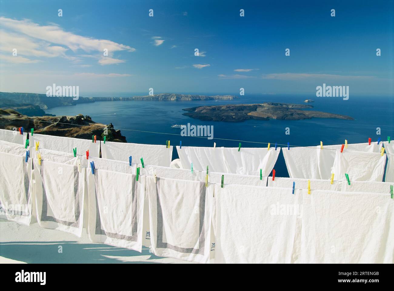 Frische weiße Bettwäsche zum Trocknen mit malerischem Blick auf das Wasser auf einem Hügel; Santorin, Griechenland Stockfoto