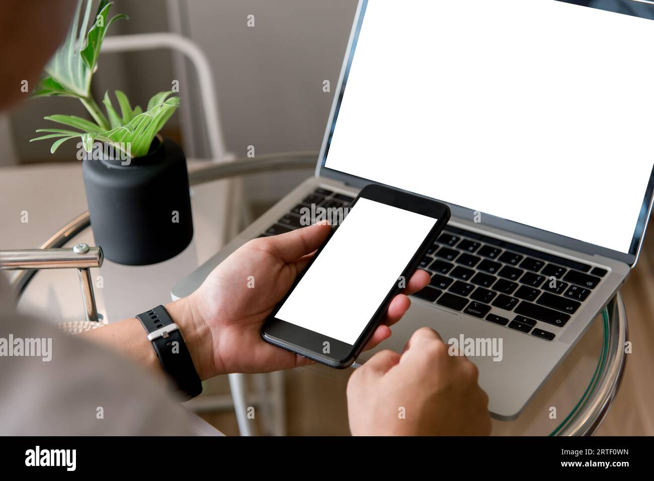 Mock-up-Mann mit Mobiltelefon und Laptop mit leerem Bildschirm modern. Kopieren Sie Raummarketing und kreatives Design Stockfoto