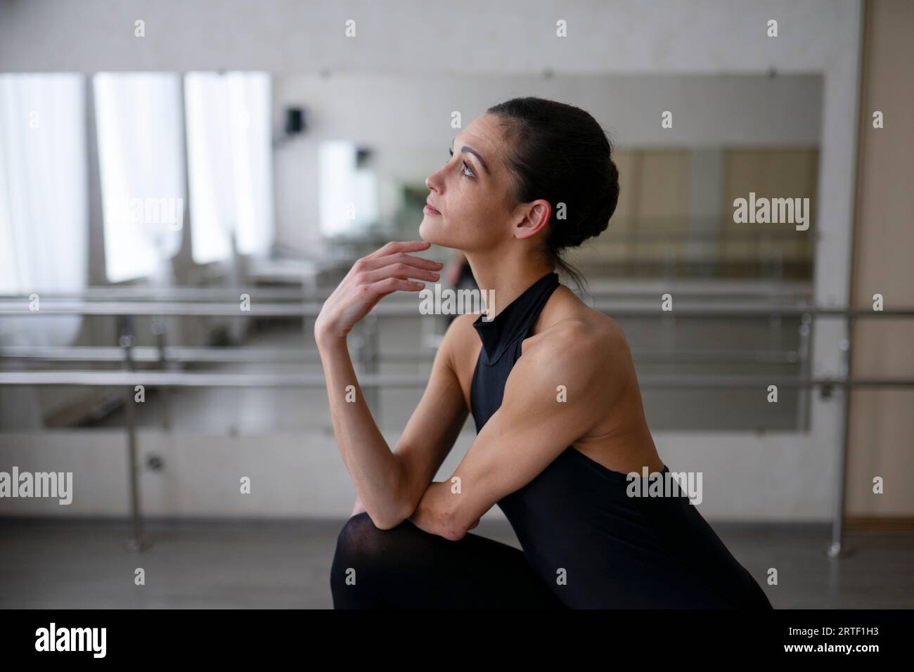 Ballerina in anmutiger Pose, die nach oben blickt und das Kinn berührt Stockfoto