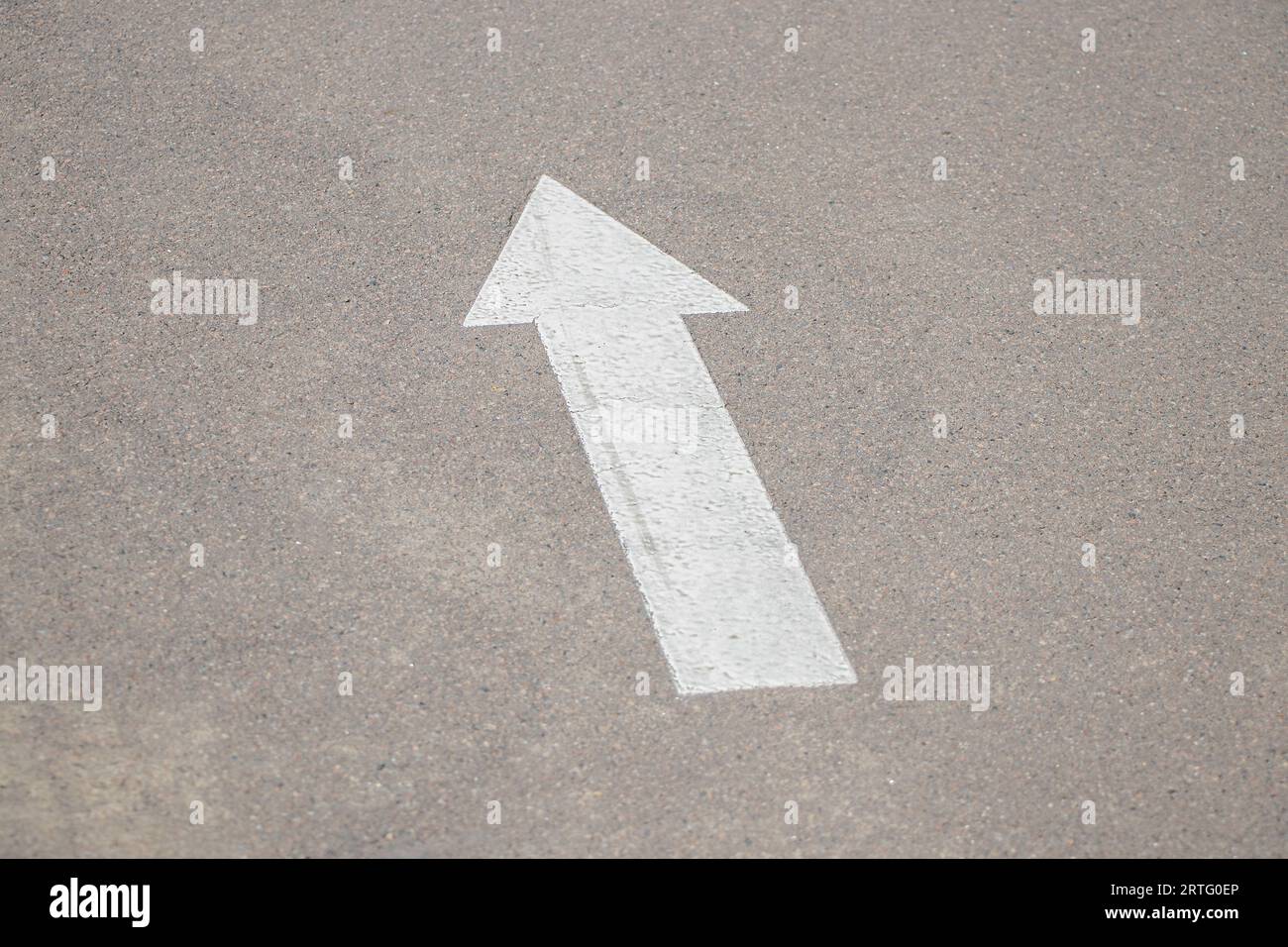 Ein weißer Pfeil, der nach vorne zeigt, wird auf dem Asphalt auf der Straße als Hintergrund, als Weg nach vorne, als Route gezeichnet Stockfoto