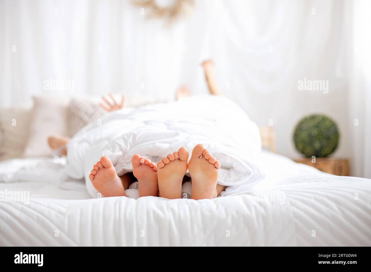 Glückliche positive Kinder, kitzeln auf den Füßen, haben Spaß zusammen, Junge und Mädchen zu Hause haben einen wundervollen Tag der Freude zusammen Stockfoto