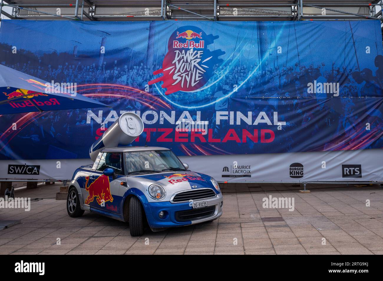 Lausanne, Waadtländer Kanton, Schweiz - 20. August 2023: Red Bull Werbung Mini Cooper Auto mit Logo. Riese Red Bull Energy Drink Dose auf dem Wagen Stockfoto