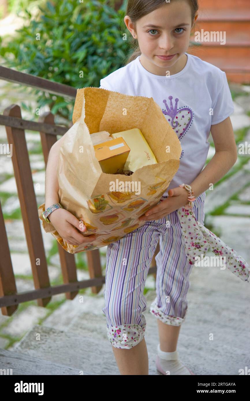 Junges Mädchen Treppensteigen trägt eine braune Papiertüte Stockfoto