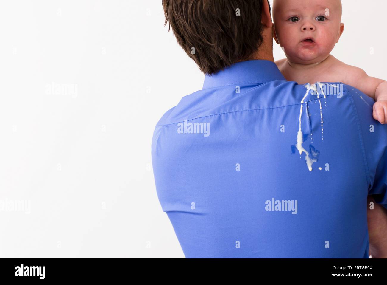 Rückansicht eines Mannes mit einem Baby mit Erbrochenem auf dem Rücken und Schulter Stockfoto