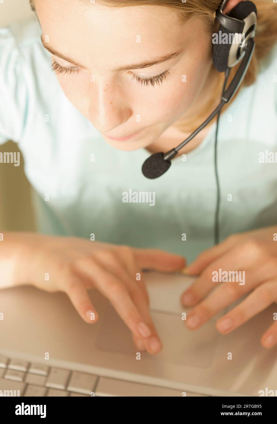 Nahaufnahme eines lächelnden jungen Mädchen trägt Kopfhörer und Mikrofon Eingabe auf einem Laptop-computer Stockfoto